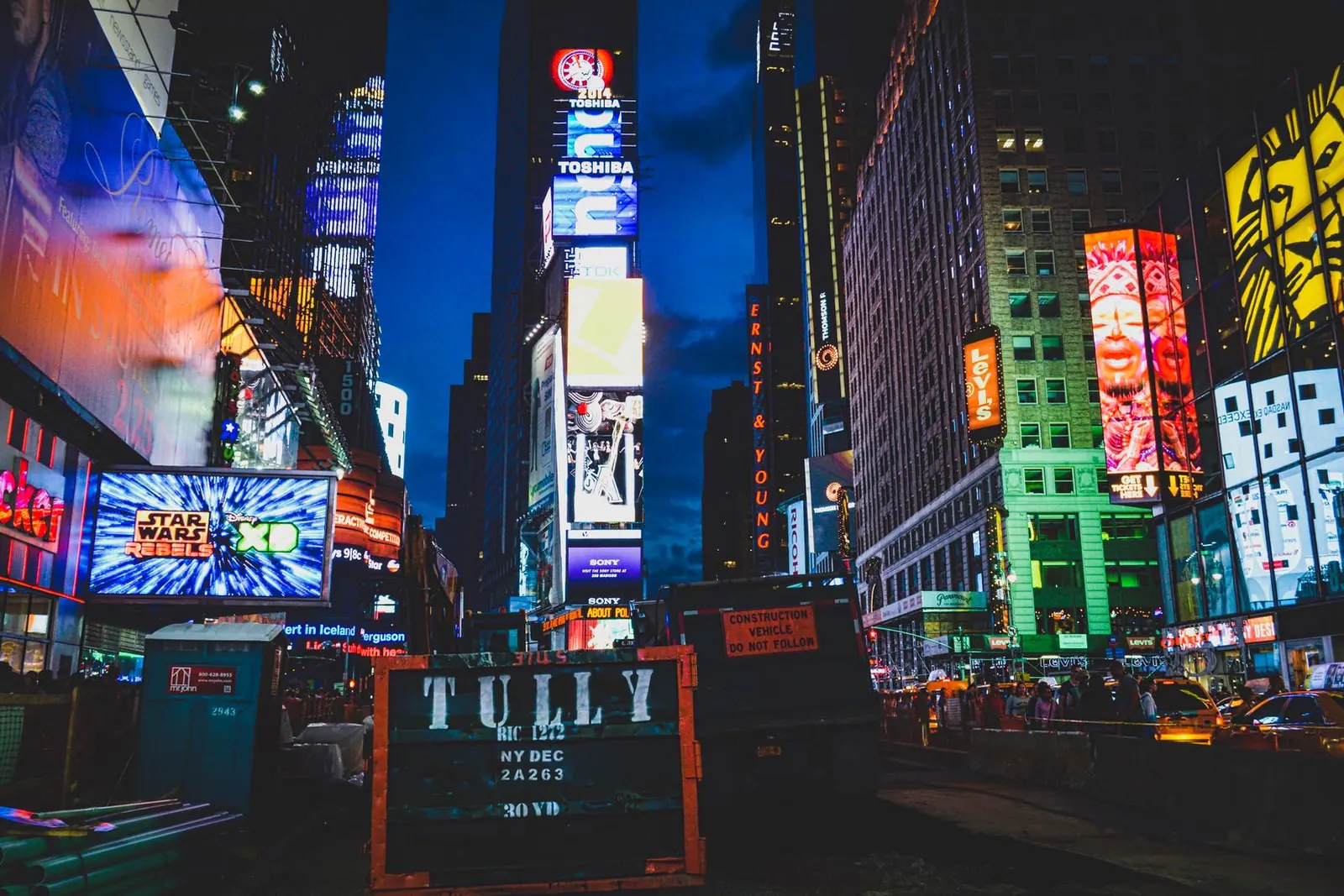 Times Square at night, lit by large brand billboards