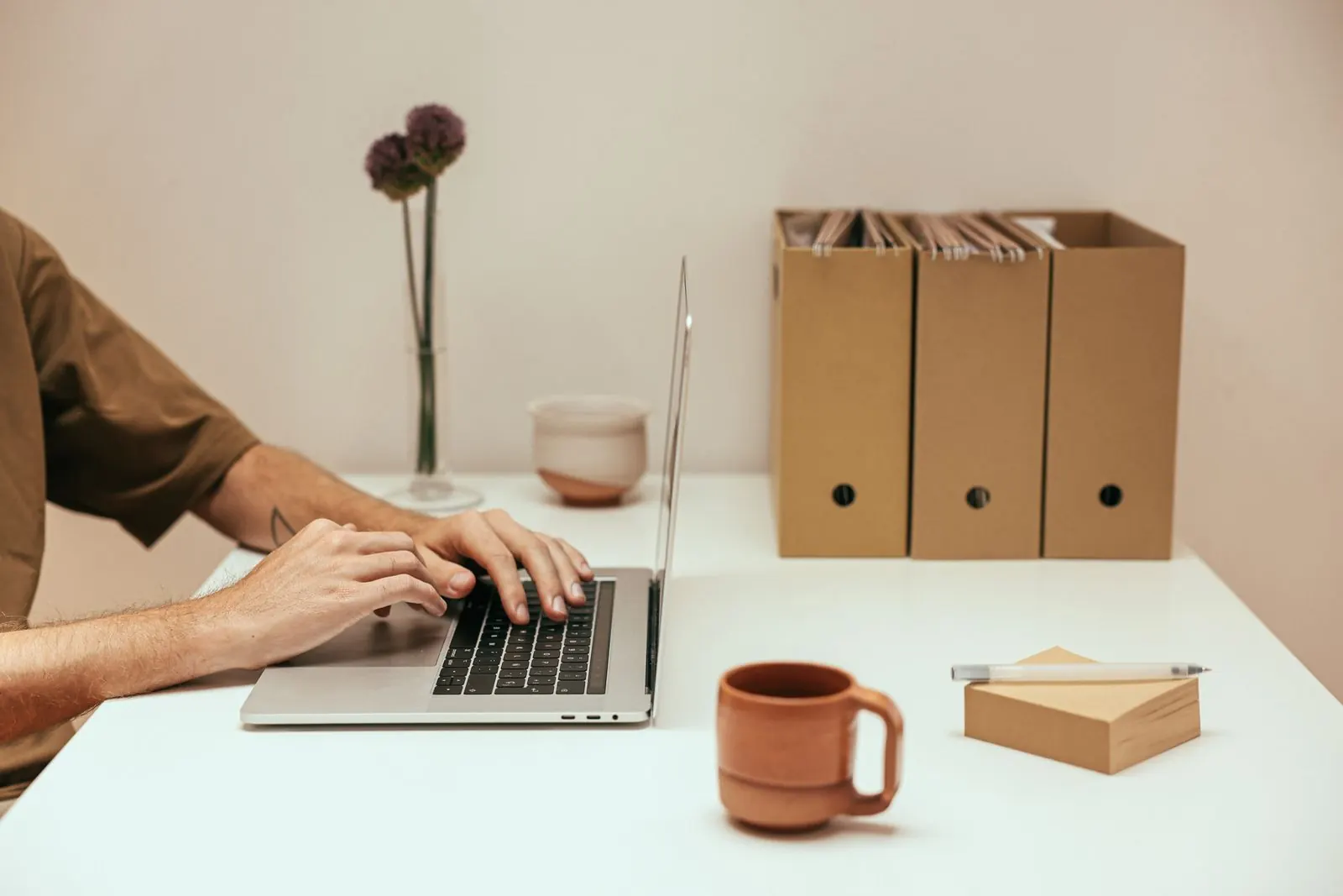 A professional working on a laptop at a tidy desk beside document boxes